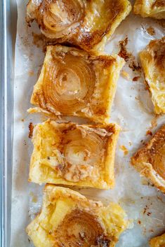 several pieces of pastry sitting on top of wax paper in a baking pan with cinnamon swirl toppings