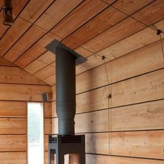 a wood burning stove sitting inside of a wooden room next to a window with no curtains