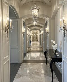 an elegant hallway with chandeliers and marble flooring is seen in this image