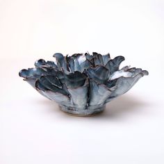 a white and blue bowl with black flowers on it's rim, against a white background