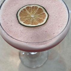 a pink drink with a slice of orange on the rim