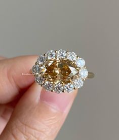 a close up of a person's hand holding an engagement ring with a fancy yellow diamond