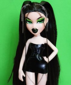 a doll with black hair and green eyes is posed in front of a green background