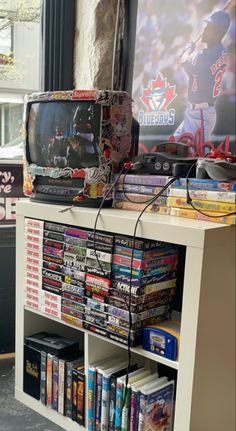 a television sitting on top of a white book shelf next to a window filled with books