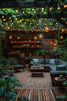 an outdoor living room with lots of plants and lights hanging from the ceiling over the couches