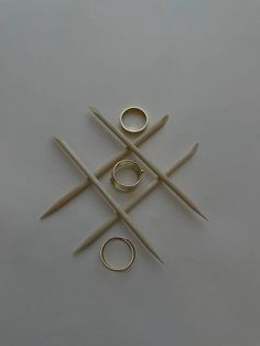 four pairs of scissors and two rings on top of a white surface with one ring in the middle