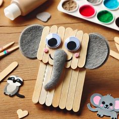 an elephant made out of popsicle sticks sitting on top of a wooden table next to other craft supplies