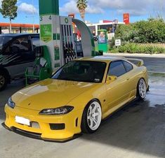 a yellow sports car parked in front of a gas station