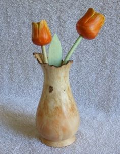 three orange tulips in a vase on a white background