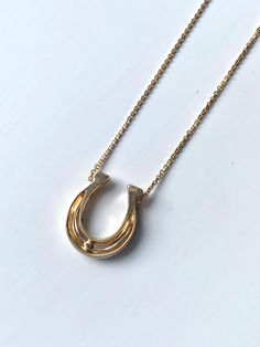 a gold necklace with an open circle on the front and bottom, sitting on a white surface