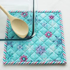 a wooden spoon sitting on top of a blue quilted placemat next to a glass container