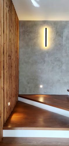 an empty room with wooden stairs and a light on the wall above it that is lit up