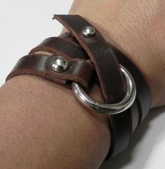 a person wearing a leather bracelet with metal rings