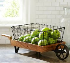 a basket filled with green tennis balls sitting on top of a wooden wheelbarrow