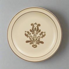 a white and gold plate with an ornate design on the front, sitting on a gray surface