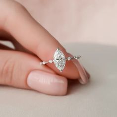 a woman's hand holding an engagement ring with a pear shaped diamond on it