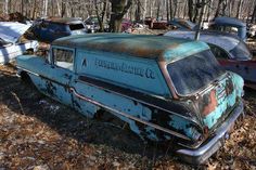 an old rusty car sitting in the woods