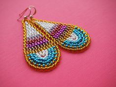 a pair of beaded earrings on a pink surface