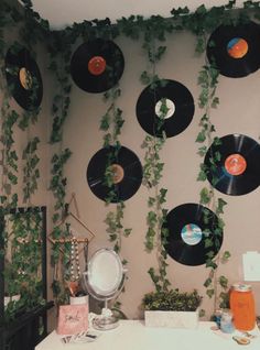 there are many records hanging on the wall with plants growing from them and in front of it