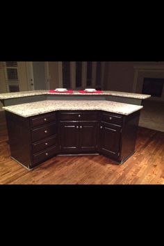 an empty kitchen with granite counter tops and dark wood cabinets, along with hardwood flooring