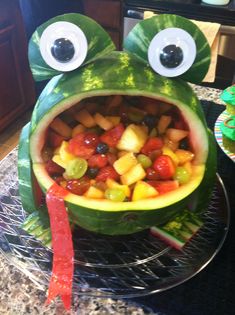 a watermelon shaped like a frog with its mouth open and fruits in it