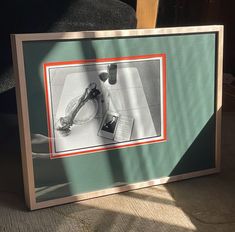 a framed photograph of a table with a book on it and a pair of scissors