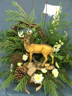 a deer figurine sitting on top of a table surrounded by flowers and pine cones