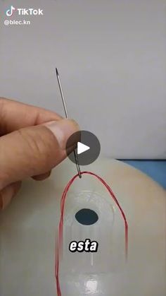 a person is using needles to cut the wire on top of a mannequin's head