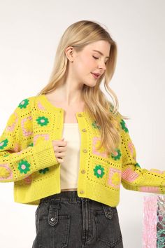 a woman wearing a yellow cardigan with flowers on it