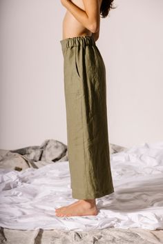 A new interpretation of our much-loved Emil Pant, the Easy Crop version has a modern, airy feel. The elastic waistband runs from hip to hip, with a smooth flat front. The utilitarian patch front pockets, sewn into topstitched vertical seams, feel spacious without adding bulk. Cut at a slightly cropped length, the Emils work well with boots, socks, tights, flats, or fuzzy slippers. In midweight linen, the Emil Easy Crop is airy yet substantial, with a swoosh-y feel. This linen feels crisp at firs Chic Olive Straight Leg Bottoms, Olive High-waisted Pants For Spring, Linen Wide Leg Parachute Pants With Side Pockets, Wide Leg Linen Parachute Pants With Side Pockets, Chic Olive Trousers, Olive Linen Bottoms With Pockets, Relaxed Fit Linen Parachute Pants With Pockets, Olive Relaxed Fit Pants For Summer, Olive Trousers For Workwear