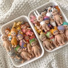 two baskets filled with small plastic toys on top of a white blanket next to each other