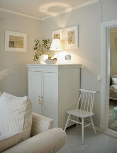 a living room with white furniture and pictures on the wall above it's cabinet