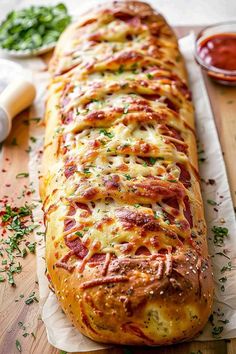 a cheesy bread is sitting on a cutting board next to some condiments