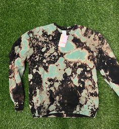 a black and blue tie dye shirt laying on the grass with a tag attached to it