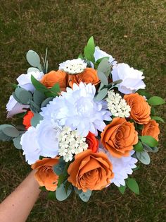 a bouquet of flowers is being held by someone's hand on the grass outside