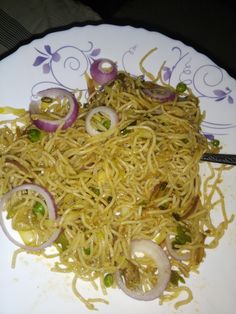 a white plate topped with noodles and onions on top of a table next to a fork