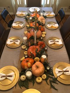 a table set for thanksgiving dinner with pumpkins, gourds and other decorations