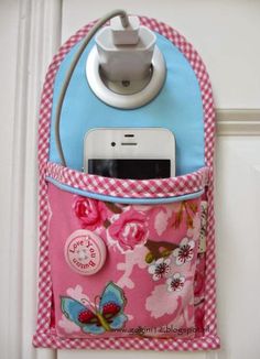 a cell phone in a pink and blue purse hanging on a door handle with a charger attached to it