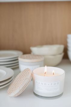 a candle sitting on top of a counter next to plates