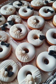 there are many decorated donuts on the trays in this case, and one is white with black bows