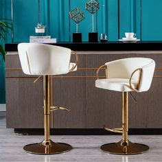 two white and gold bar stools in front of a counter with a blue wall