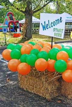 an orange and green balloon arrangement in front of a sign that says welcome to start here