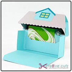 an open blue box with a paper cut out of it and a house on top