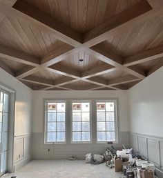 an empty room with wood paneling on the ceiling and two windows in the wall