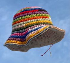 a multicolored crocheted hat is flying in the air against a blue sky