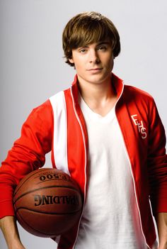 a young man is holding a basketball in his right hand and posing for the camera