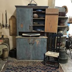 an old fashioned kitchen cabinet is in the middle of a room filled with antique items