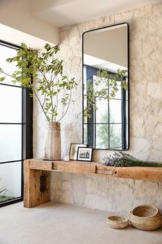 there is a mirror and some plants on the shelf in this room with stone walls