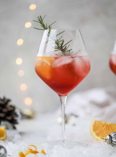 two glasses filled with red liquid and garnished with rosemary