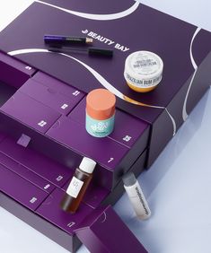 an assortment of beauty products are displayed on a purple box